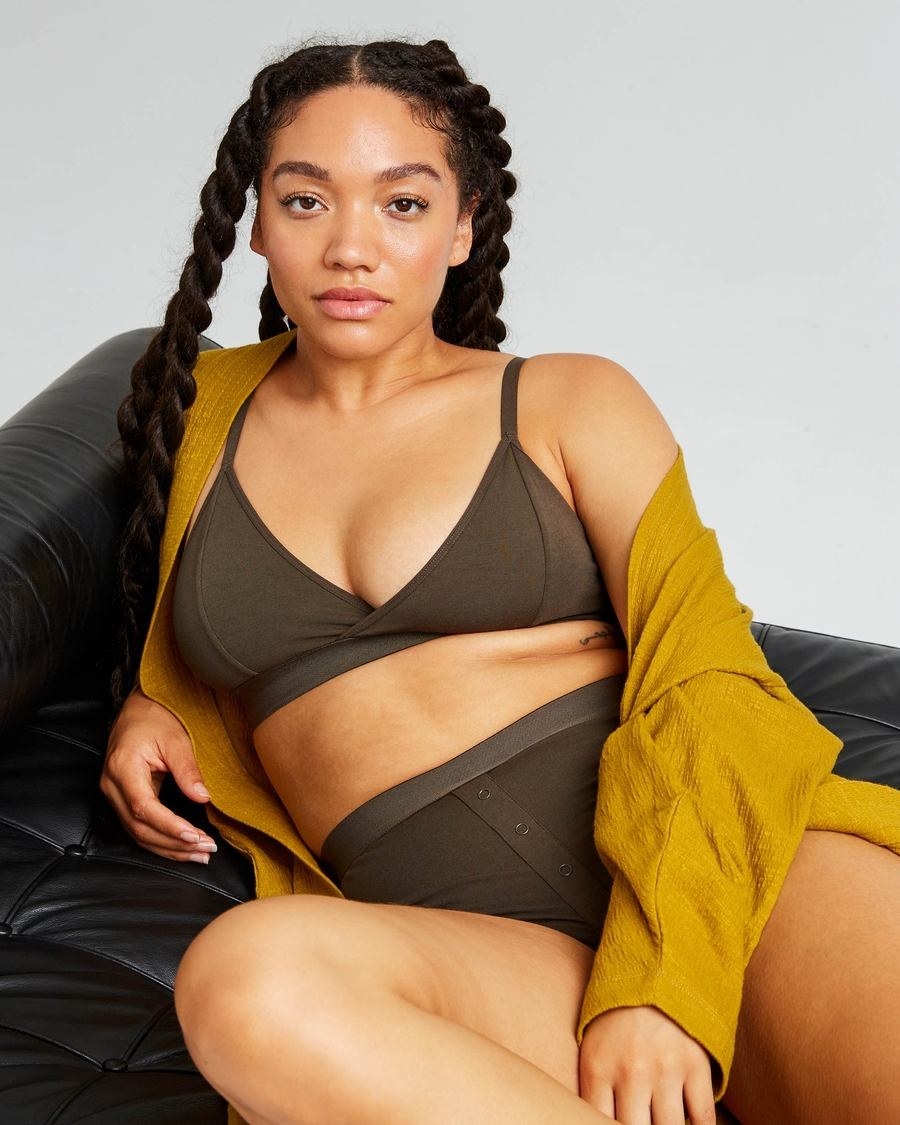 Model wearing the deep v bralette and matching boxer shorts with buttons down the middle in olive green. 