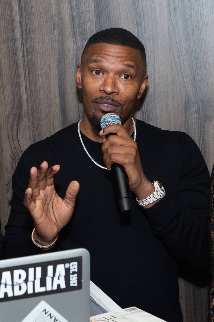 Jamie Foxx holding a microphone wearing a dark outfit