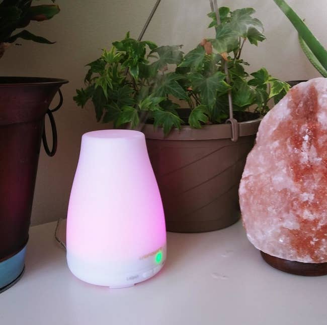 Reviewer pic of a small white diffuser lit up pink. 