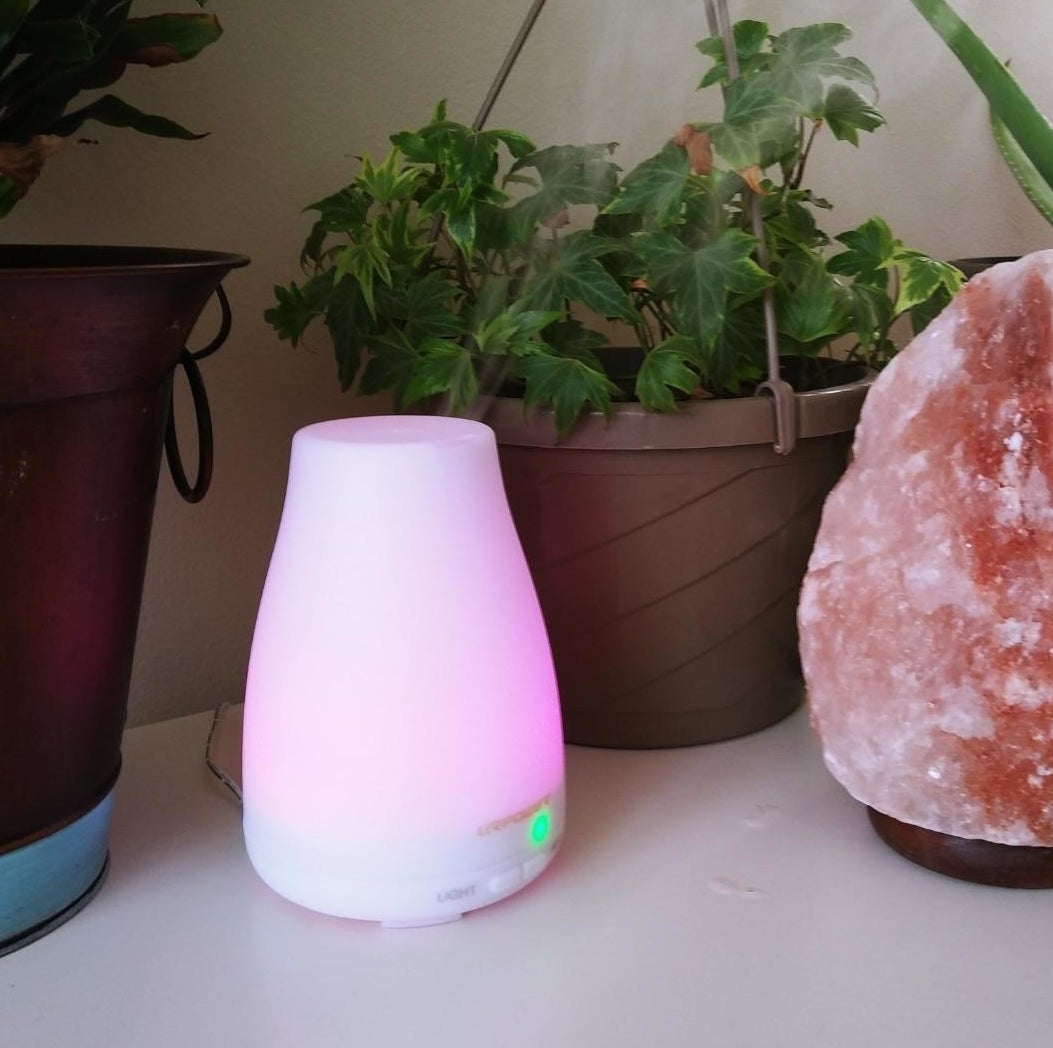 Reviewer pic of a small white diffuser lit up pink.