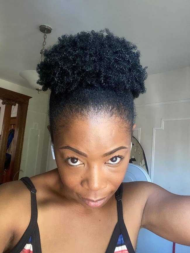 A reviewer with 4C hair styled in a puff