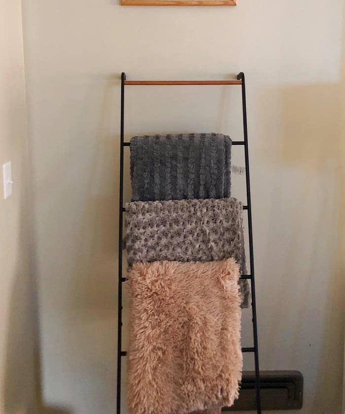 Reviewer pic of the leaning ladder in black against the wall with blankets hanging over it. 