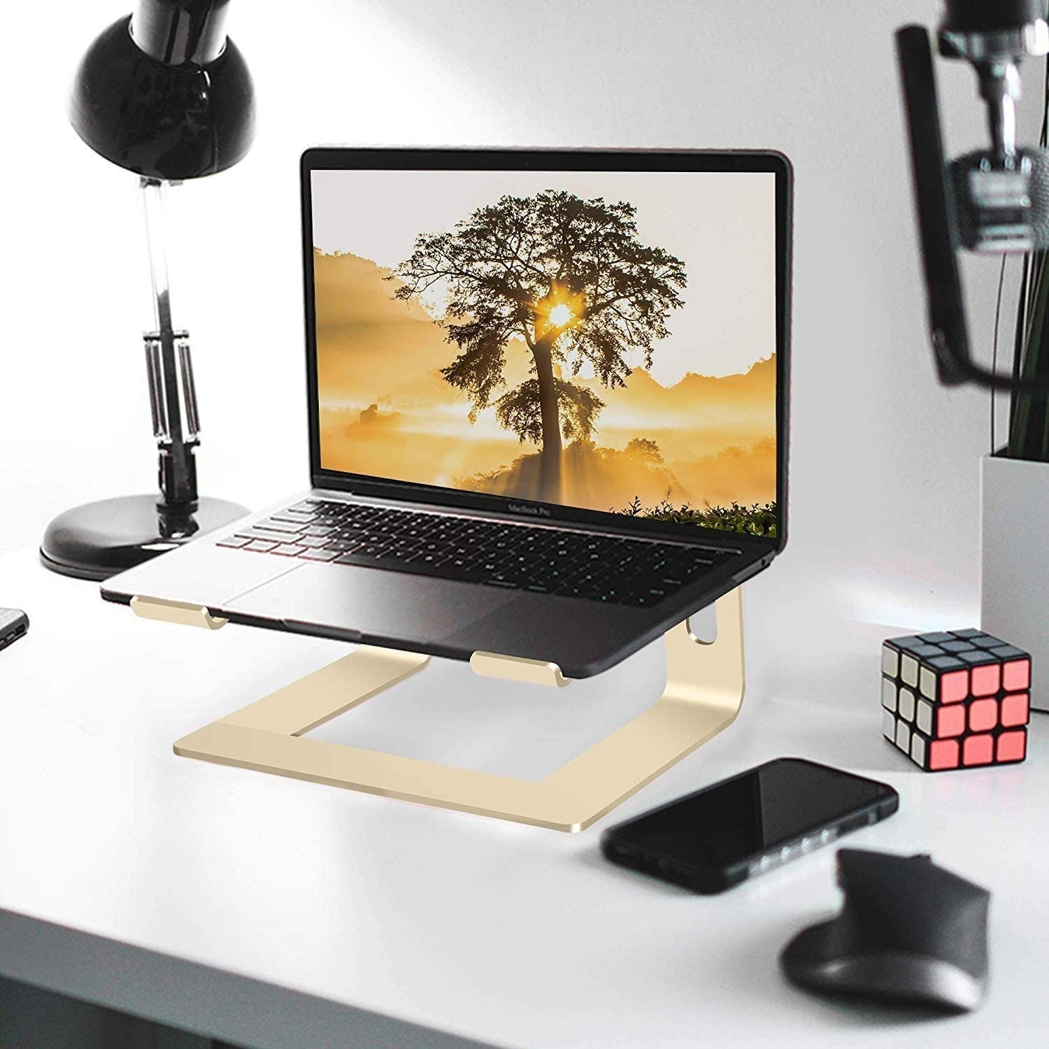 A slim aluminum laptop stand elevating a computer on a desk