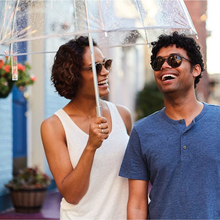 A smiling couple share the bubble umbrella