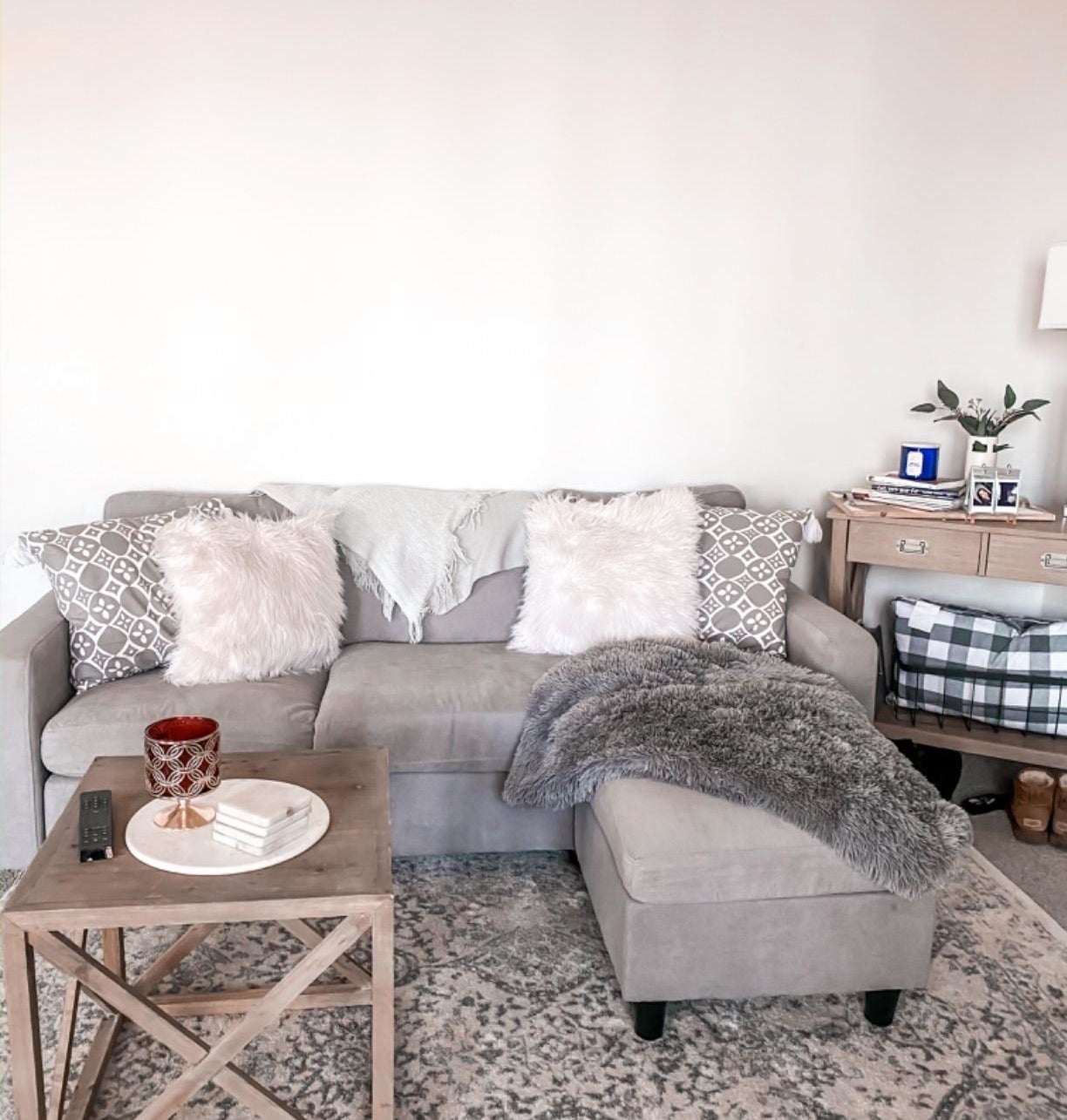 Reviewer pic of the couch in grey with an ottoman, making it into an l-shaped couch in a living room.