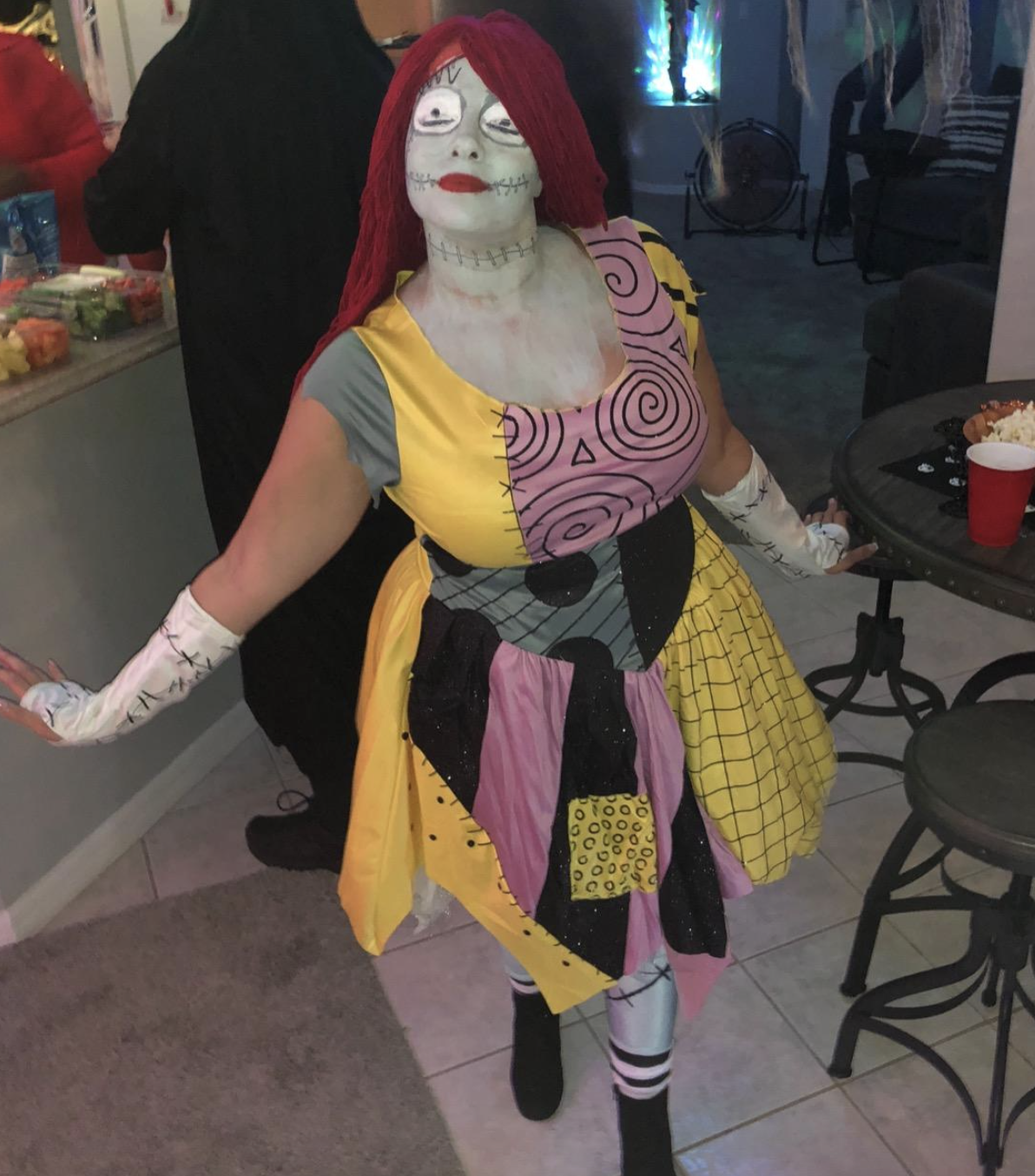 reviewer wearing patchwork dress, red wig, and blue body paint