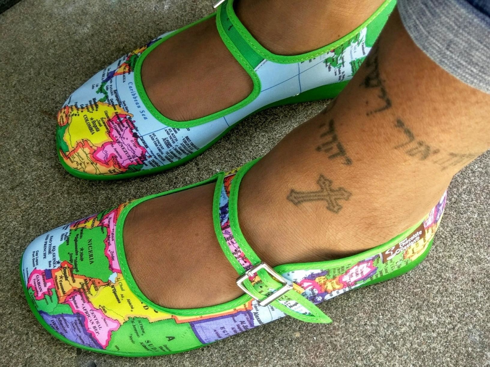 A reviewer wearing the green, blue, yellow, purple, and pink world map flats