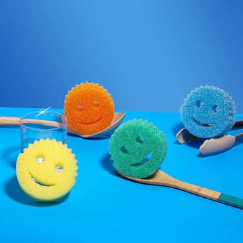 Four round, 1-inch thick smiley-faces sponges with two holes for eyes and a crescent-shaped hole for a mouth