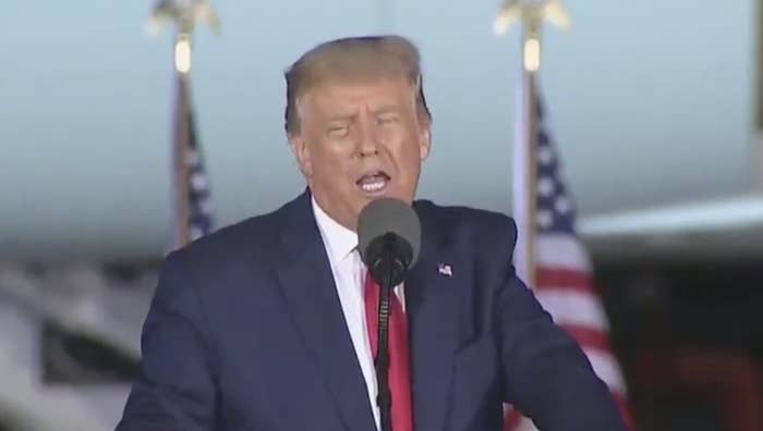 Trump speaking at a podium in front of a crowd, lying