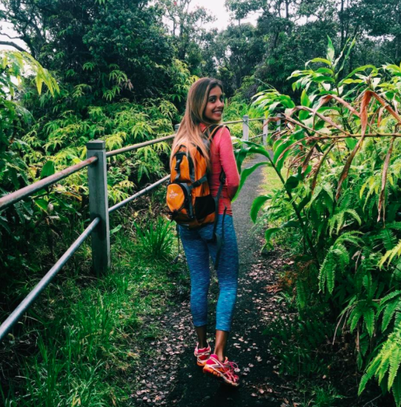 Reviewer wears orange hydration pack with blue leggings, a pink compression top, and pink sneakers while enjoying a hike in Hawaii