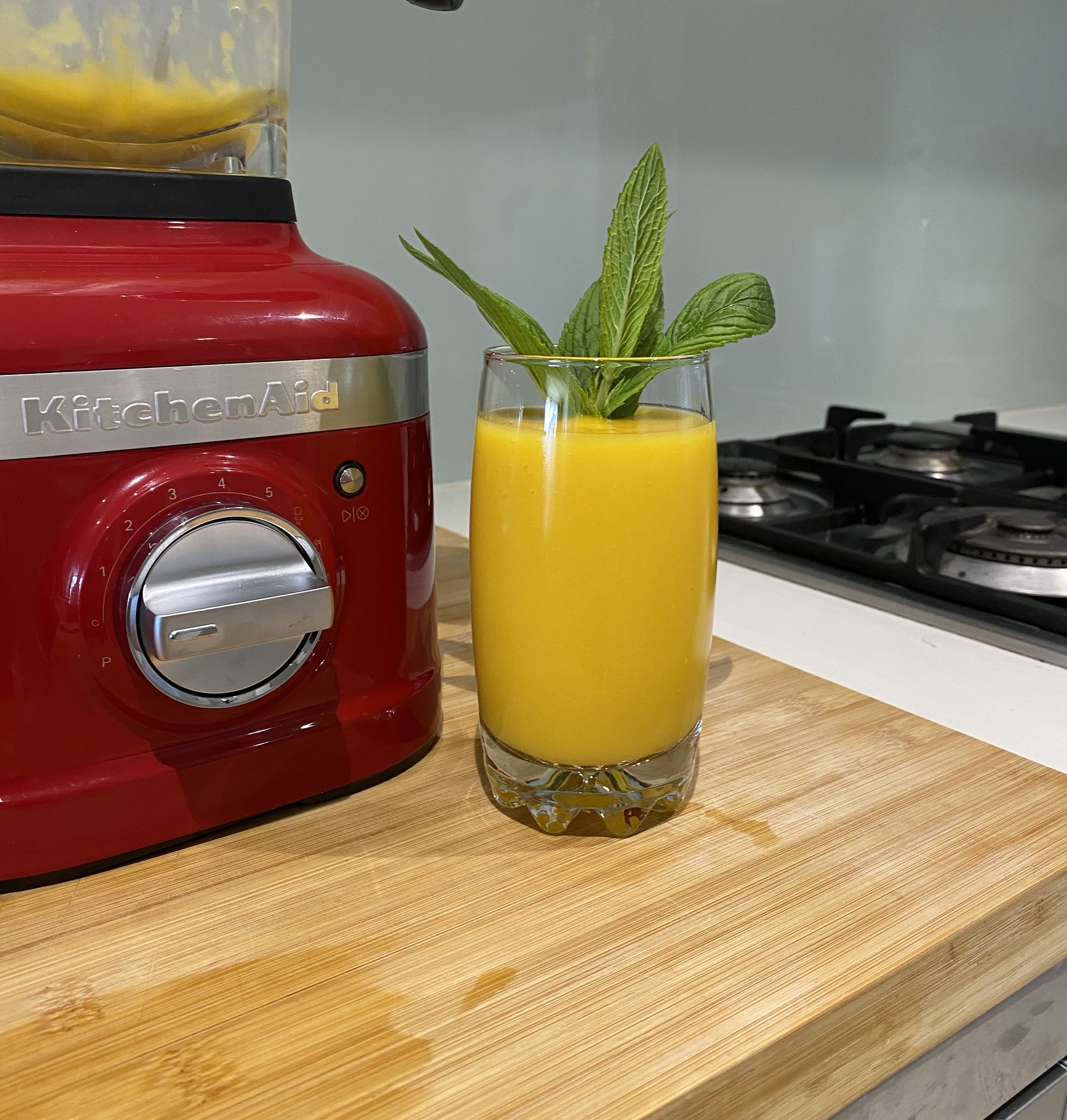 Picture of a delicious mango drink with a mint garnish next to the KitchenAid K400 Blender