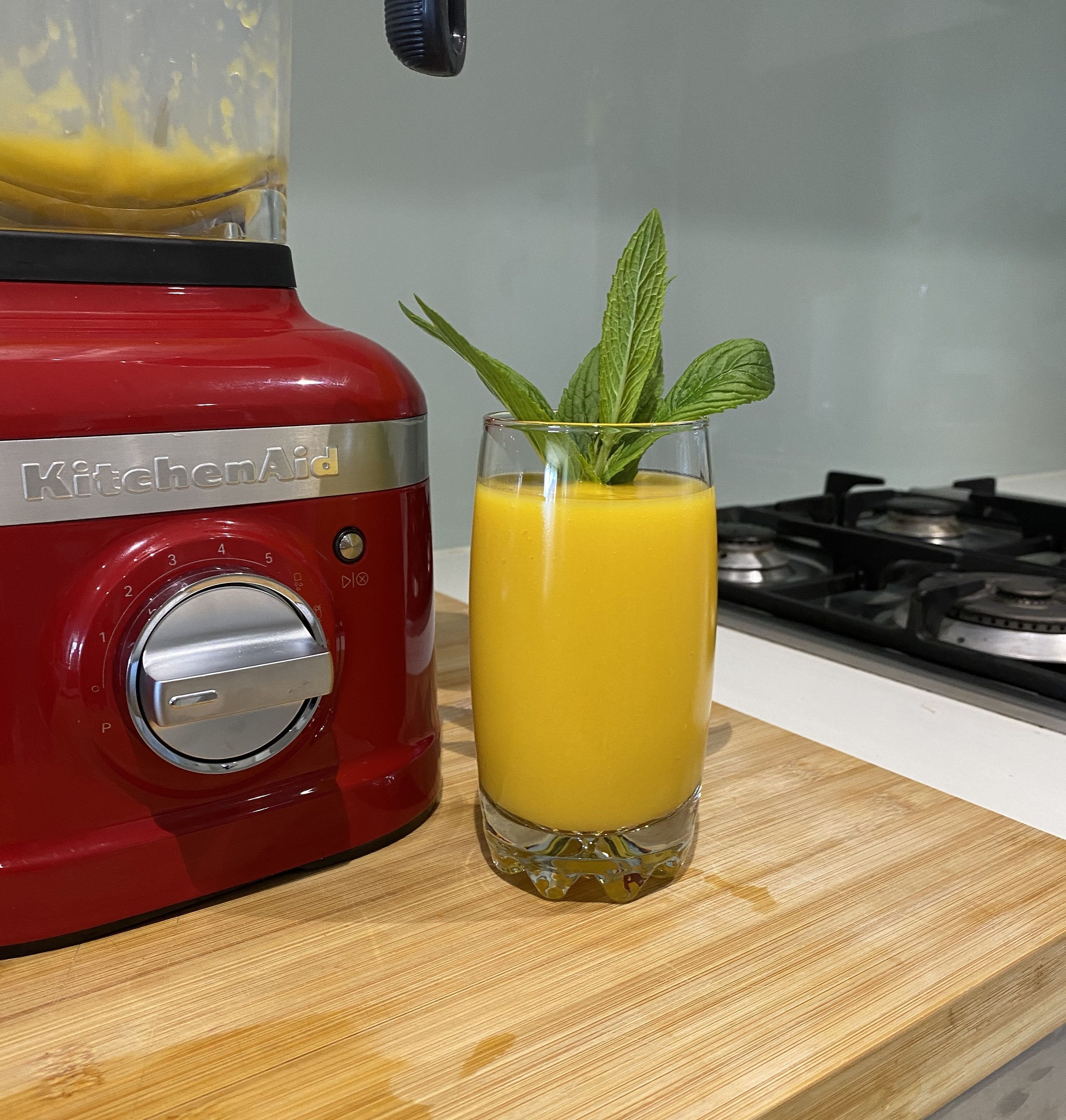 Picture of a delicious mango drink with a mint garnish next to the KitchenAid K400 Blender