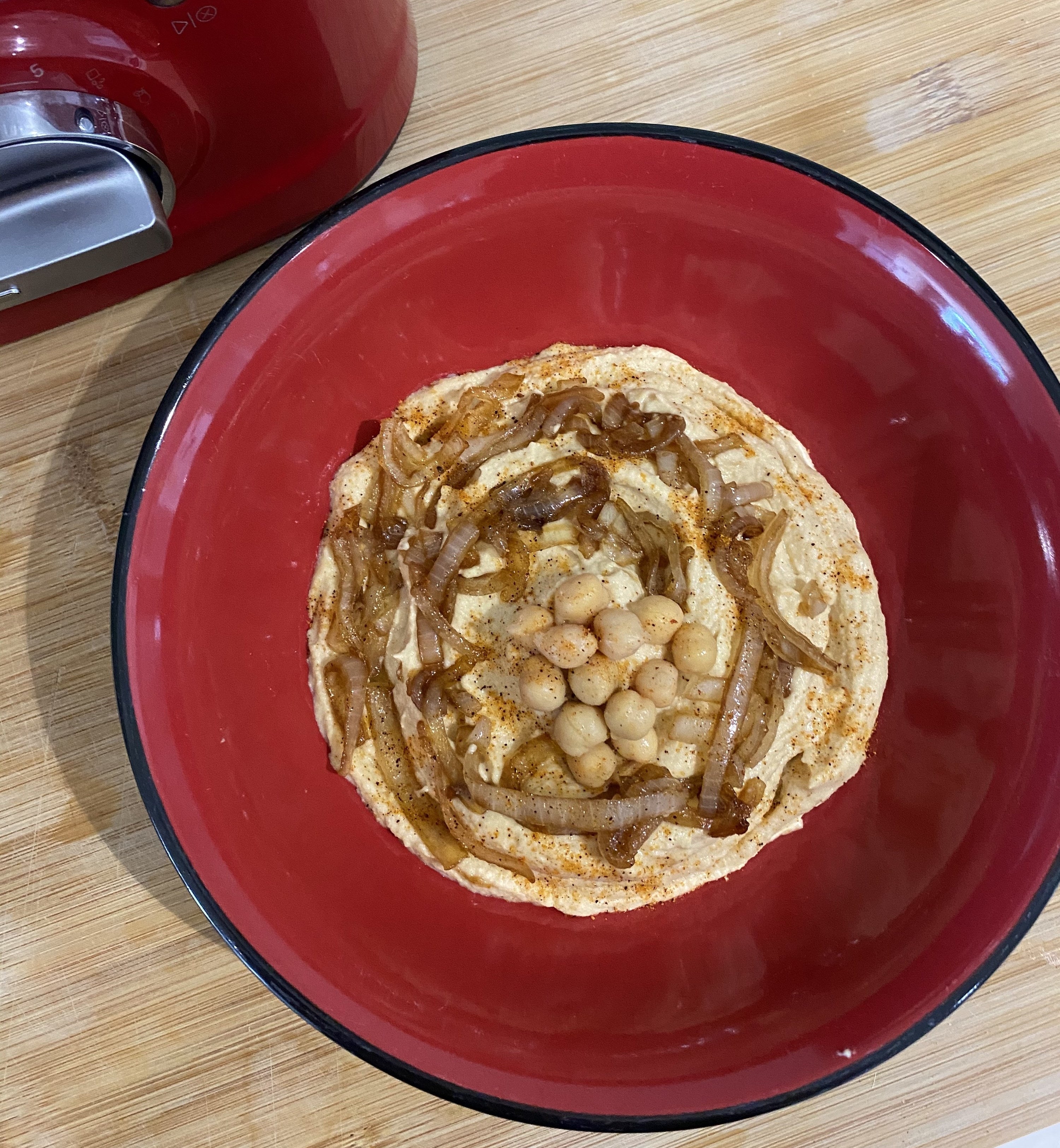 A bowl of caramelised onion hommus with chickpeas and onion garnish