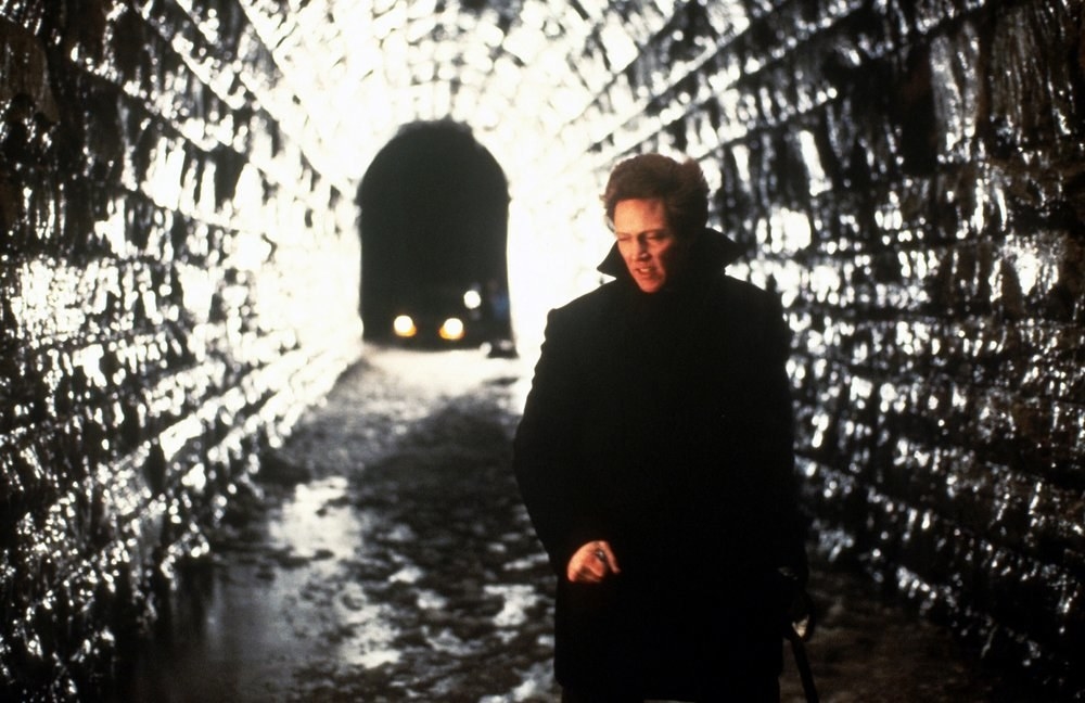 Johnny Smith walking through a dark, damp tunnel