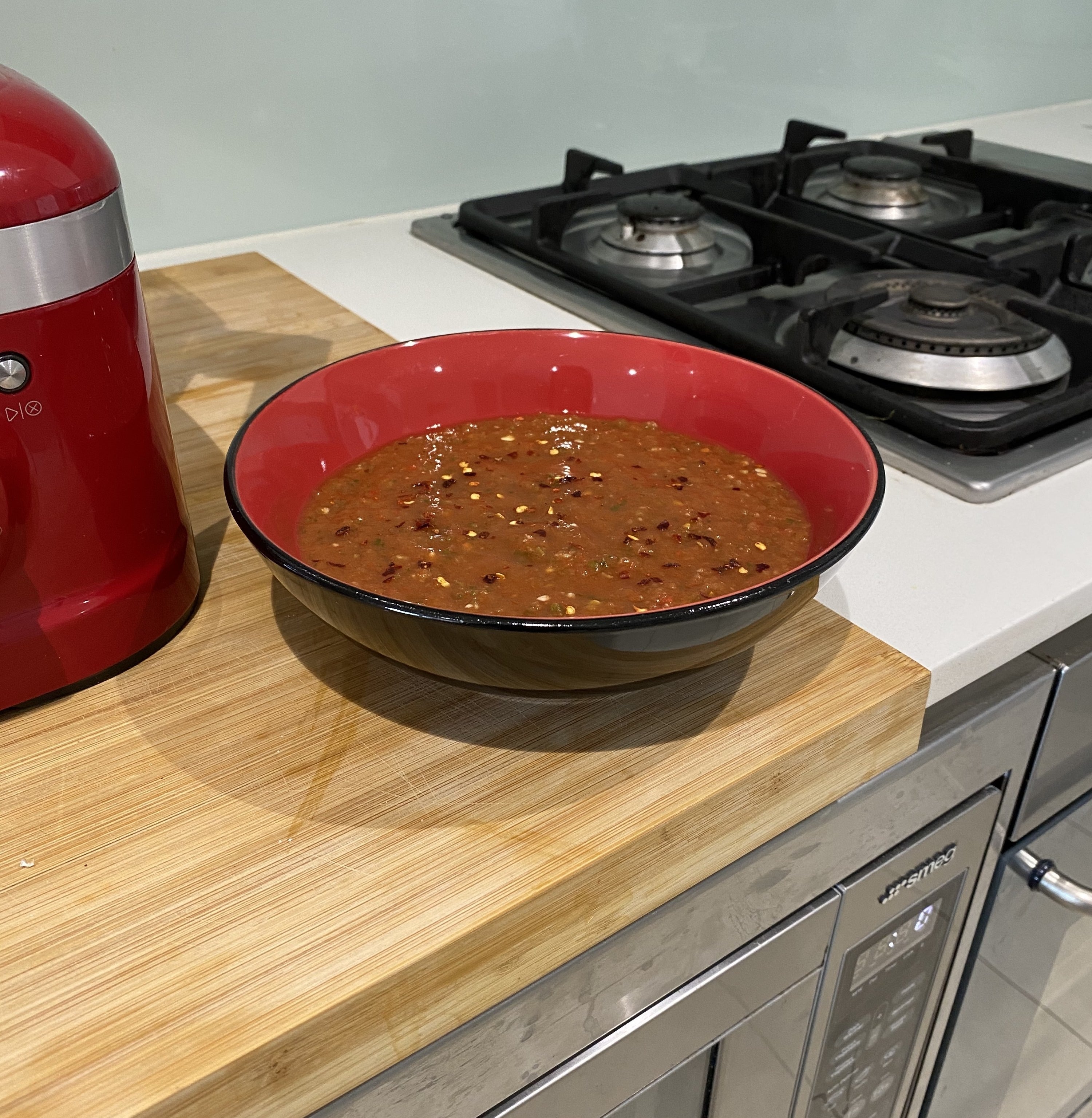 Bowl of spicy tomato salsa sitting on a bench next to the blender