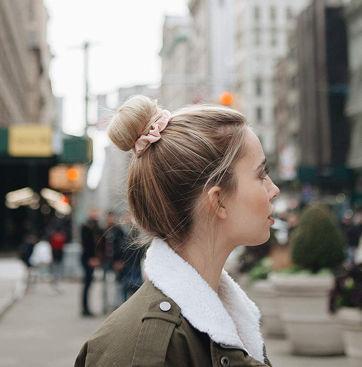 A person using a sating scrunchie to hold their bun in place