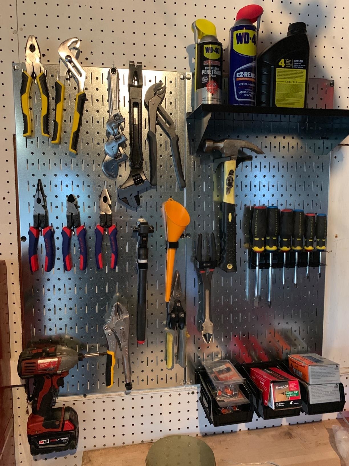 A reviewer&#x27;s photo of the metal peg board filled with tools