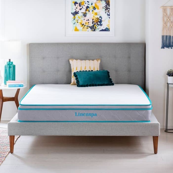 A light gray mattress with teal-colored piping and logo 