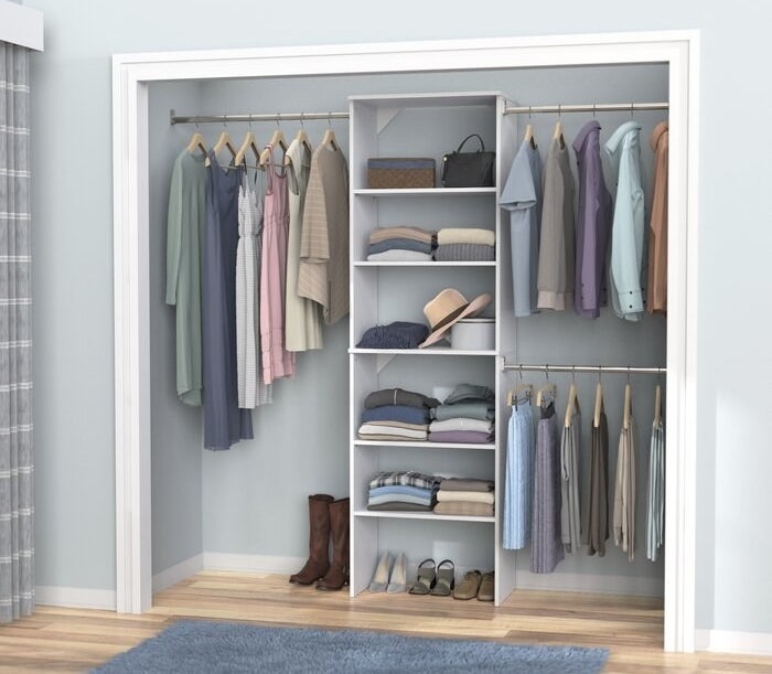 The closet system featuring three hanging rods, and a tiered shelf
