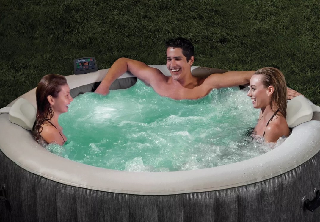 A blow-up hot tub filed with water with three people in it