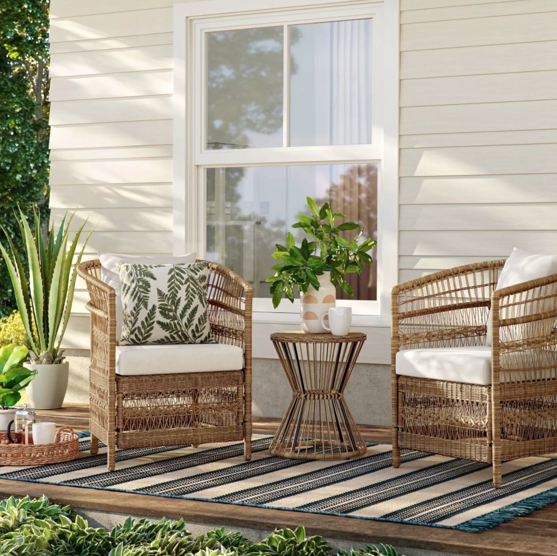 Wicker chairs and a small side table with pillows and a vase