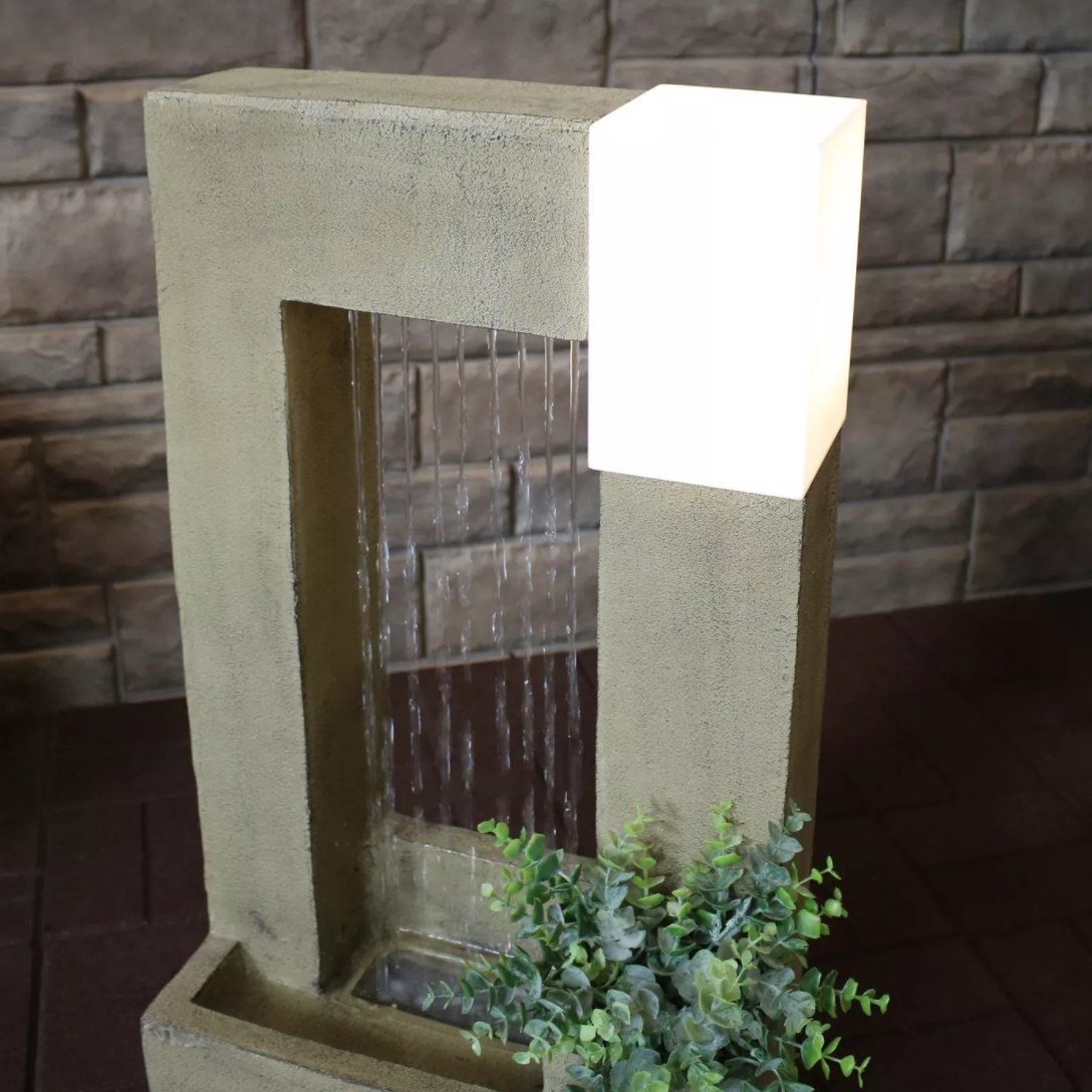 Decorative water fountain with a light and a plant in it and water flowing