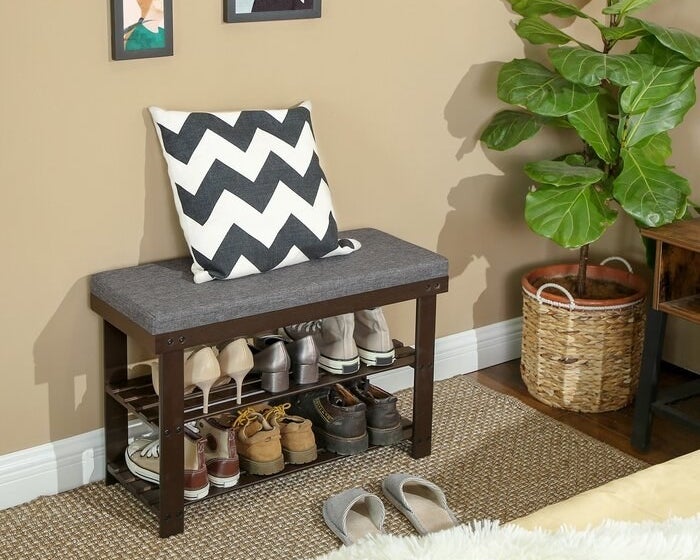 A shoe rack storage bench with six pairs of shoes being stored on it (three on each tier)