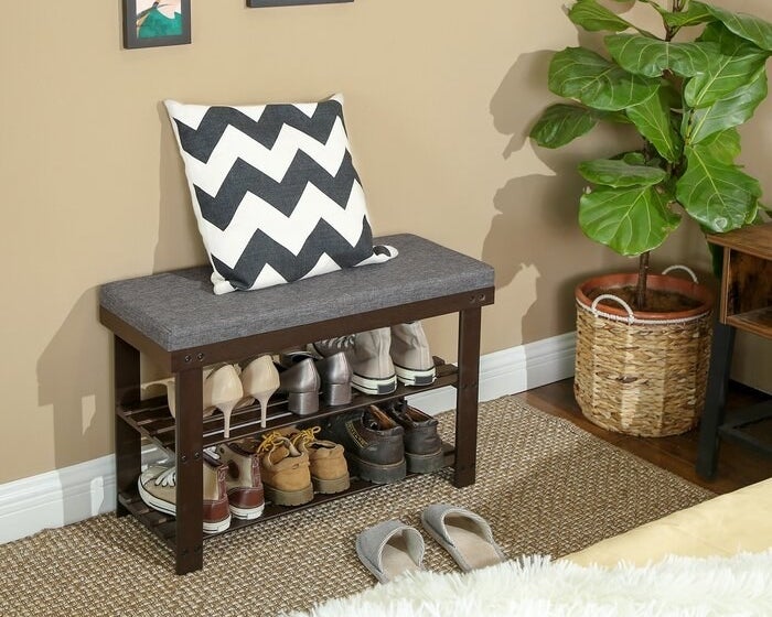 A shoe rack storage bench with six pairs of shoes being stored on it (three on each tier)