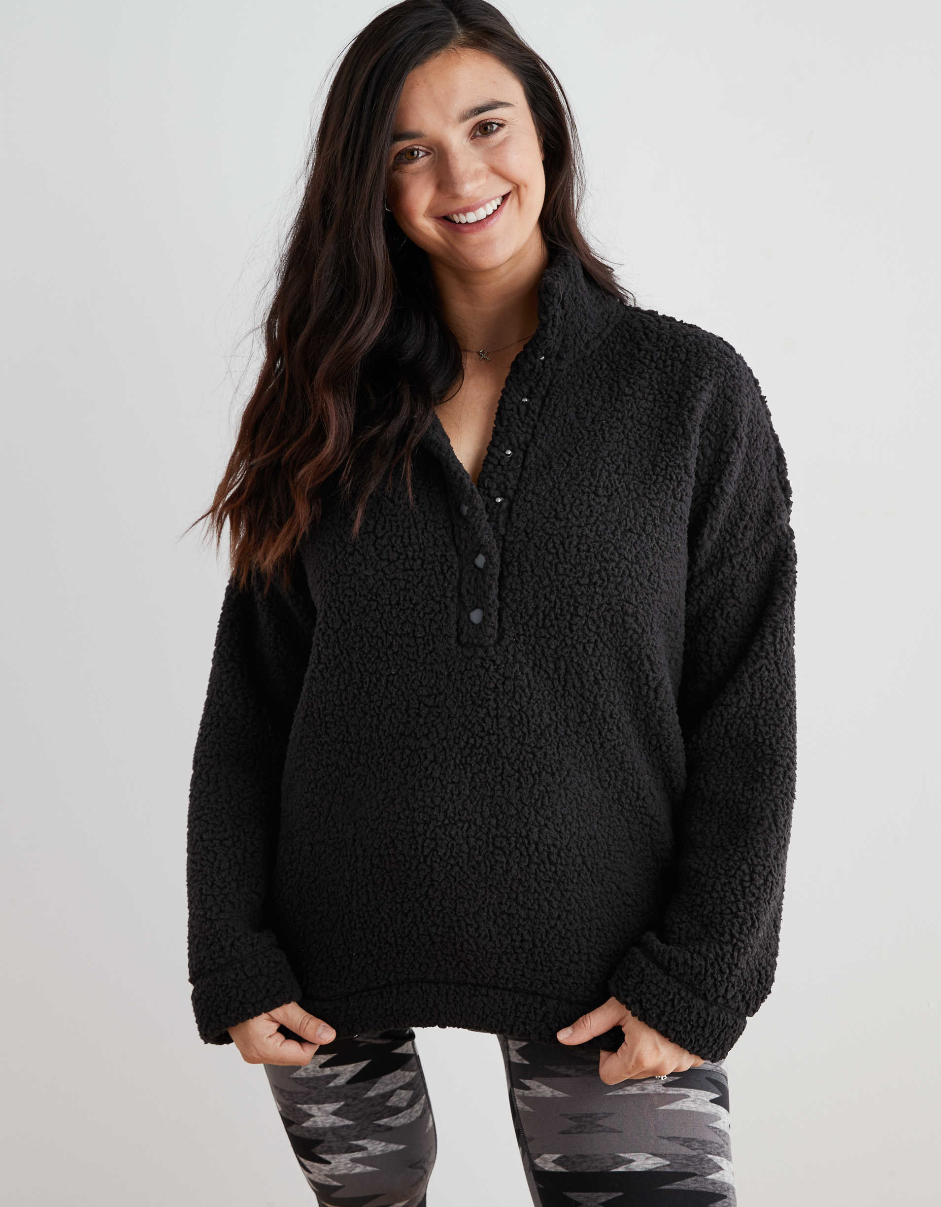 Model wearing the fuzzy sweatshirt in black with snaps a quarter of the way down the middle