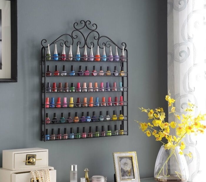 The organizer hanging on a wall holding numerous colors of nail polish