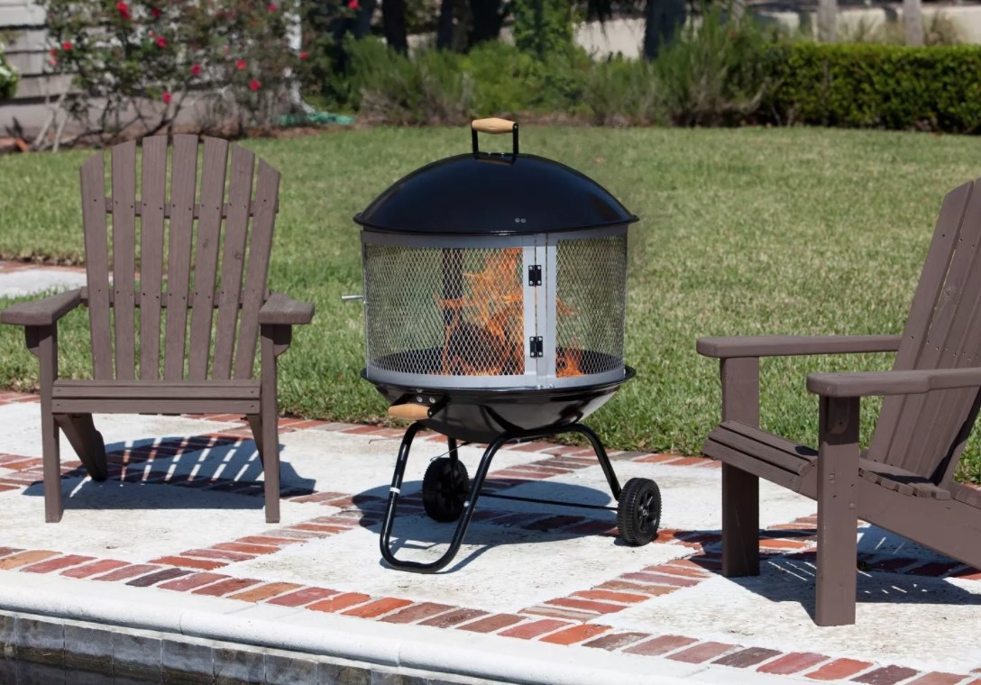 A fire place on wheels next to two Adirondack chairs