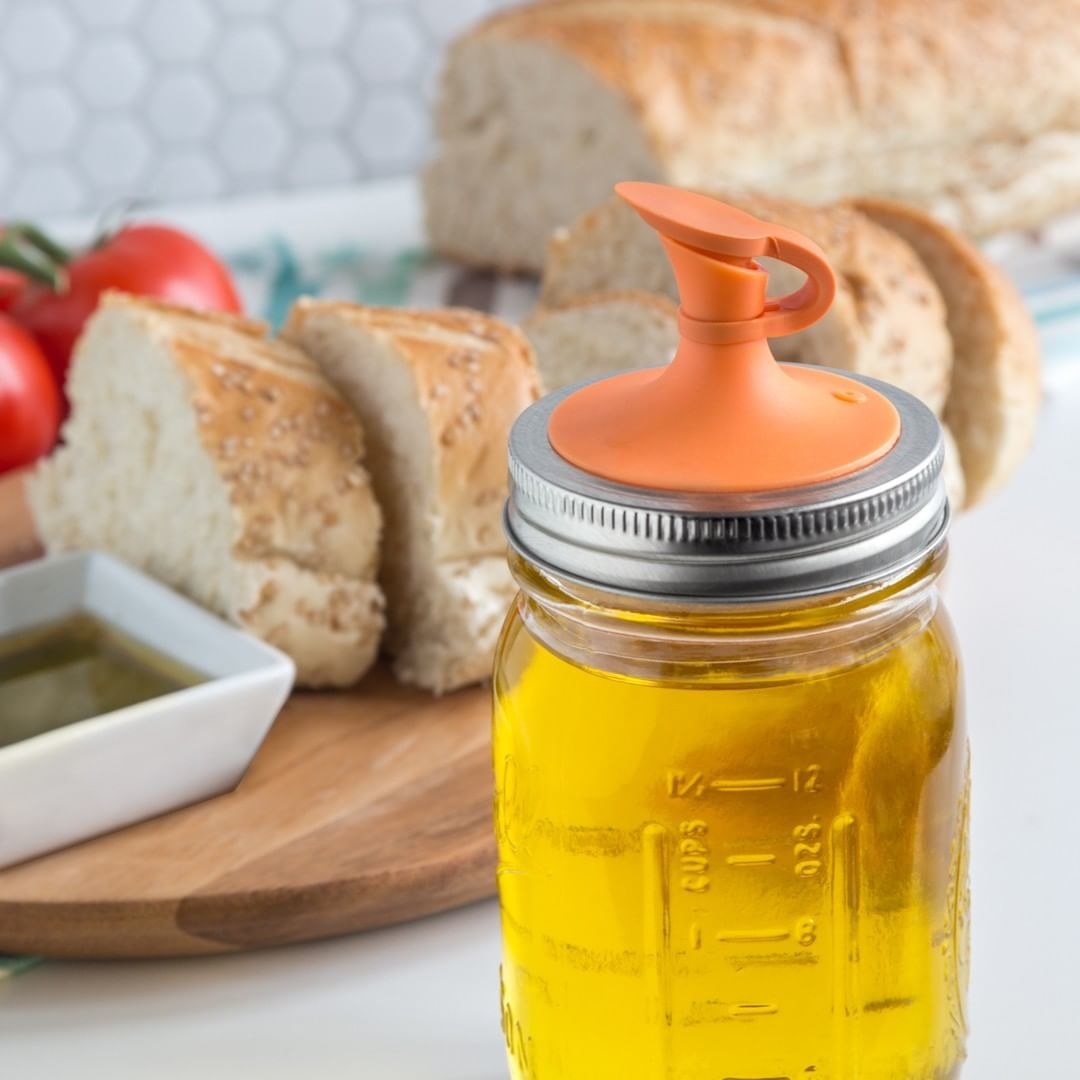 A close up of the spout and lid attached to a Mason jar full of oil