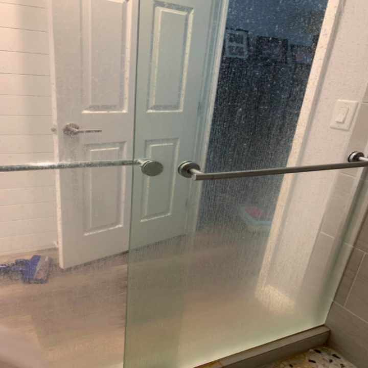 Reviewer's shower door with water stains before using the water stain remover