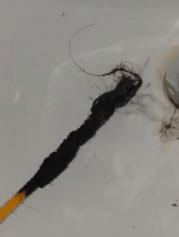 Reviewer shows gross hair and gunk lifted out of drain by yellow FlexiSnake Drain Millipede 