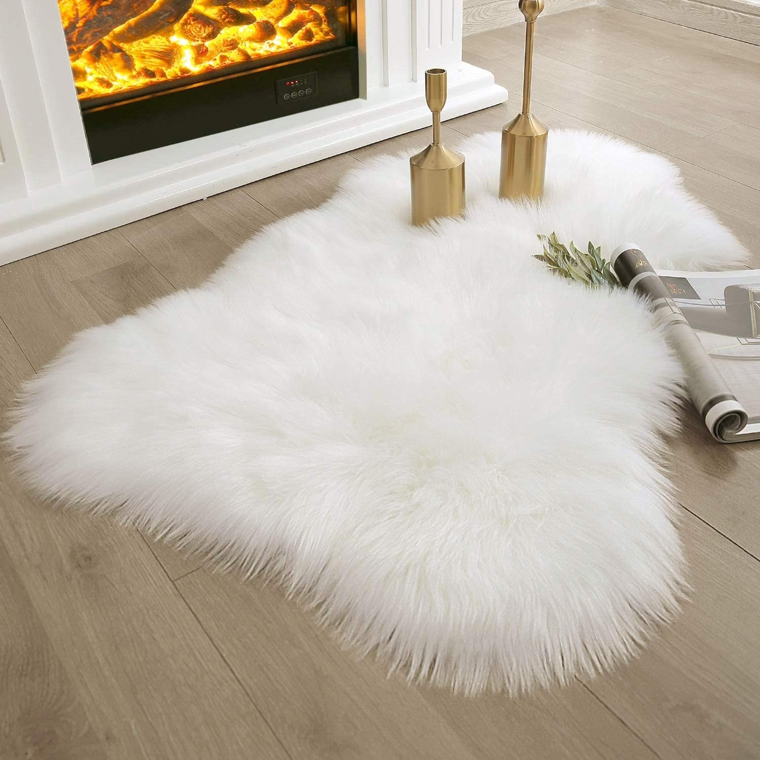a small, asymmetrical sheepskin-shaped rug with white faux fur in front of a fireplace