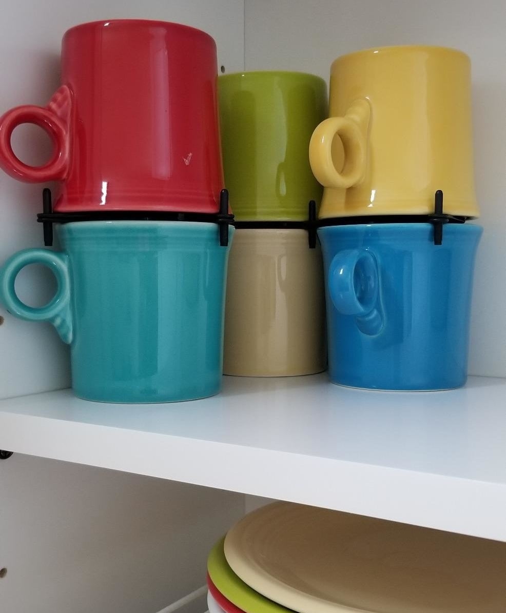 Black organizers allowing colorful mugs to be stacked on top of each other