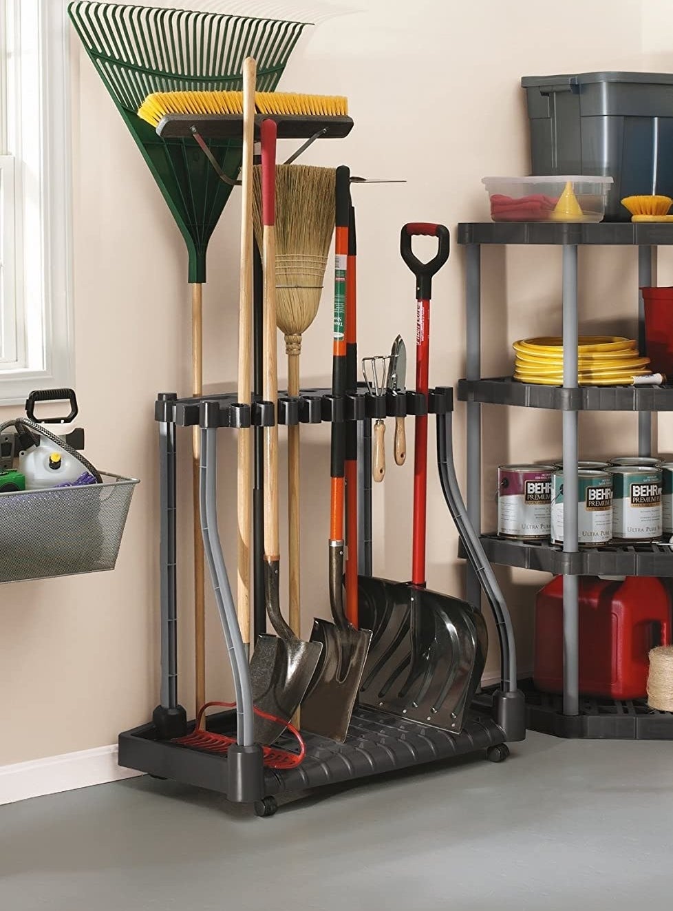 A black and gray plastic tool organizer on caster wheels holding rakes, shovels, and more outdoor tools