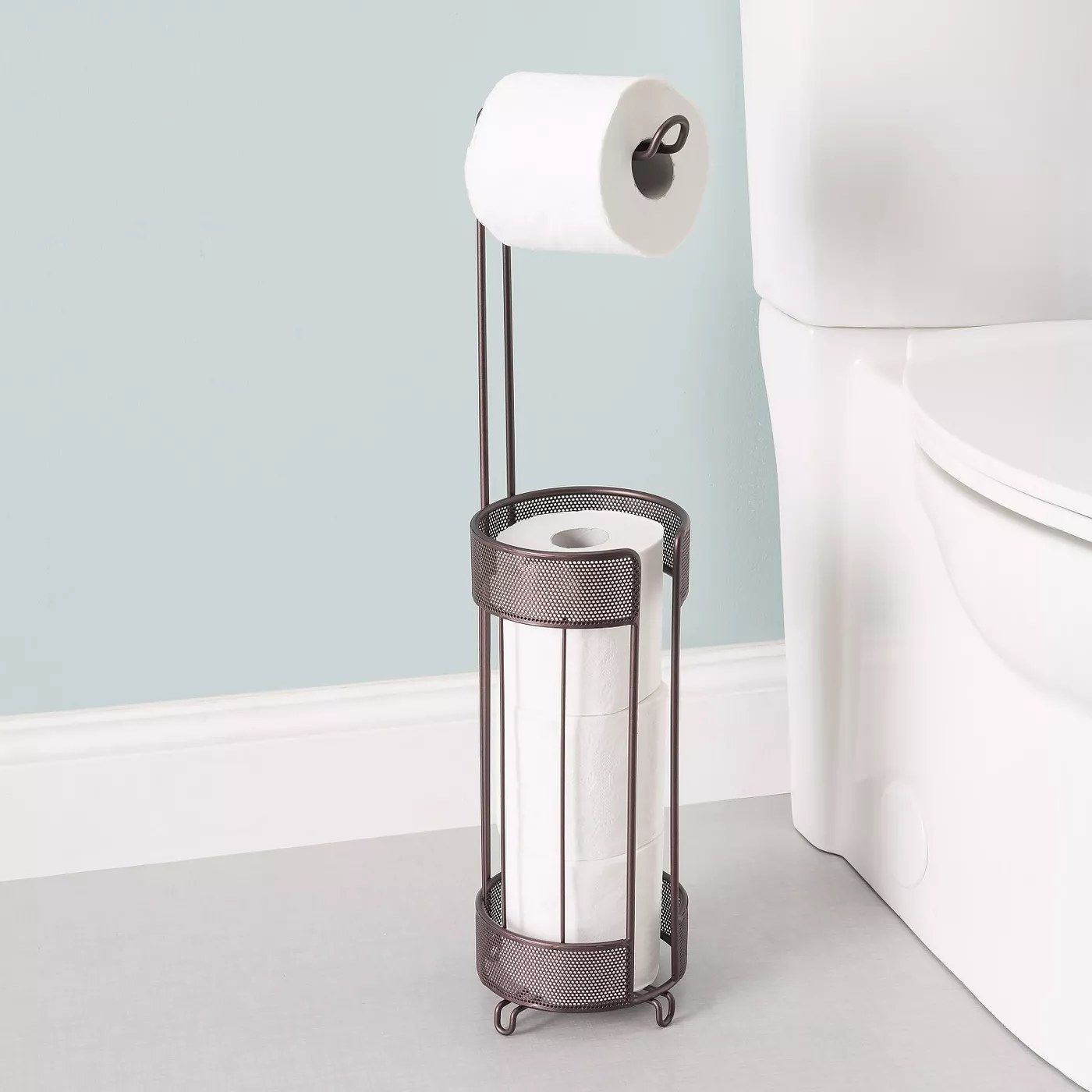 The bronze toilet paper dispenser holding four rolls of toilet paper