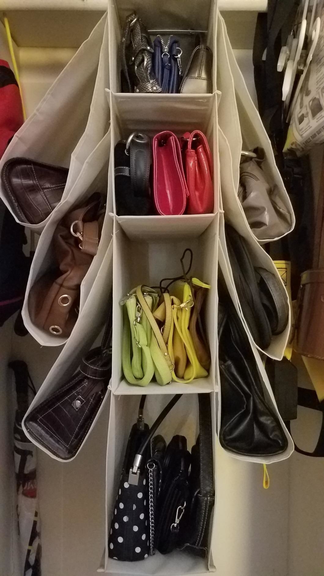 A tan-colored cloth handbag storage rack with metal hooks hanging in a closet