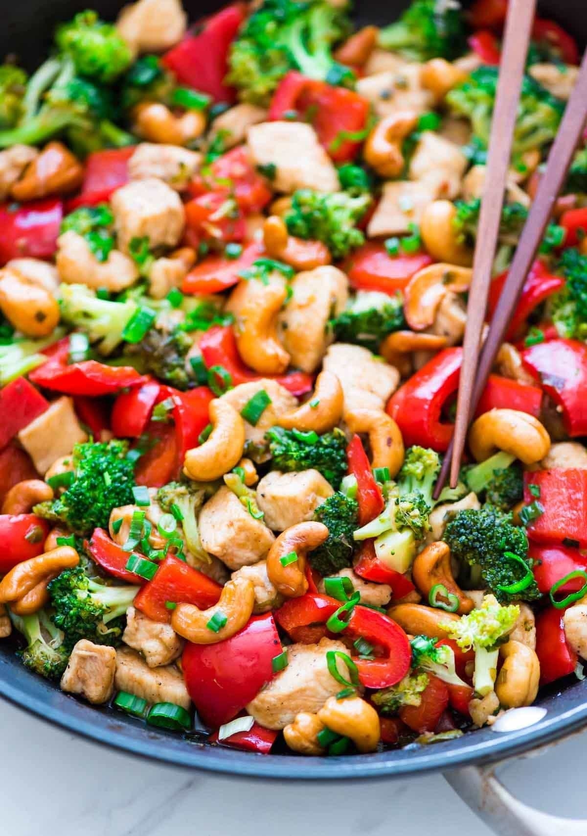 A big bowl of cashew chicken with bell pepper, broccoli, and scallions.