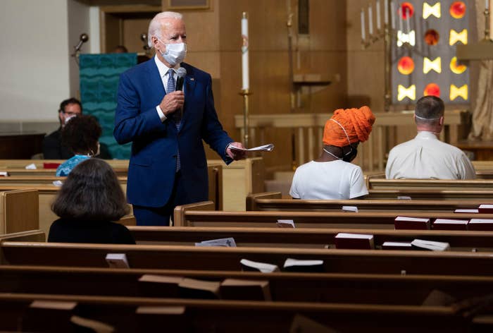 Joe Biden wears a face mask and holds a microphone