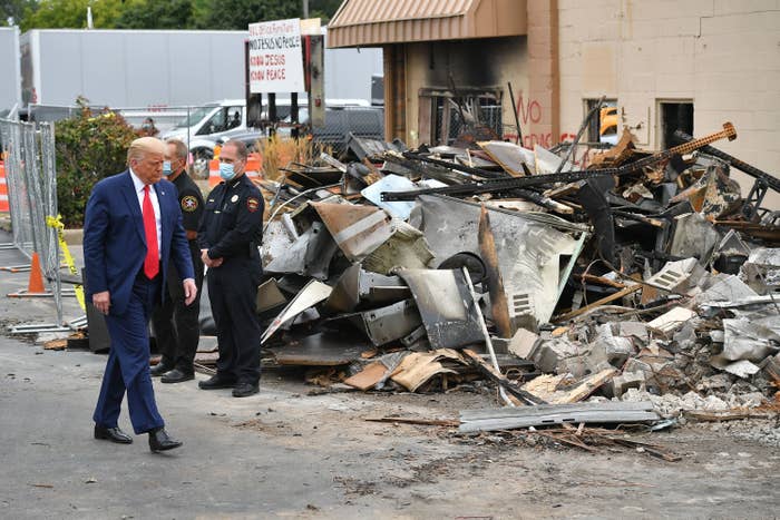 Donald Trump walks by debris of a damaged building