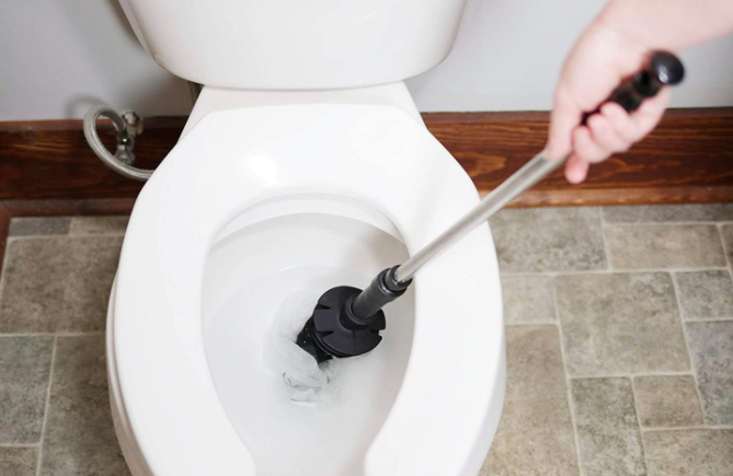 Hand uses black and silver ToiletShroom to unclog a toilet