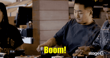 A man cracks an egg into a boiling pot of jjigae, Korean soup