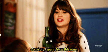 Zooey Deschanel in "New Girl" holding up a bottle of wine.