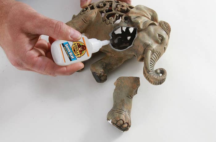 A person gluing a leg back onto a ceramic elephant with super glue