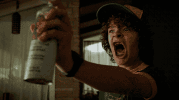 Dustin from Stranger Things screaming and spraying something from an aerosol can