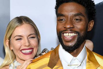 Sienna Miller playfully leaning on Chadwick Boseman's shoulder as he smiles