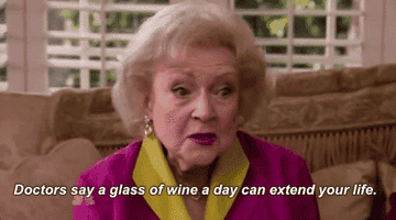 Betty White drinking a giant glass of wine with a friend on her TV show.