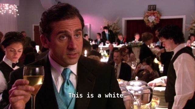 Michael Scott from &quot;The Office&quot; holding a glass of white wine at a fancy event. 